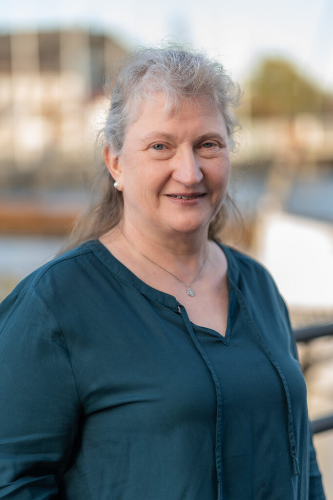 Mitarbeiterin der Steuerkanzlei vor unscharfer Hafenlandschaft.